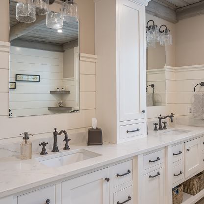 Bright bathroom vanity with double sinks, white cabinets, dark faucets, and large mirrors.