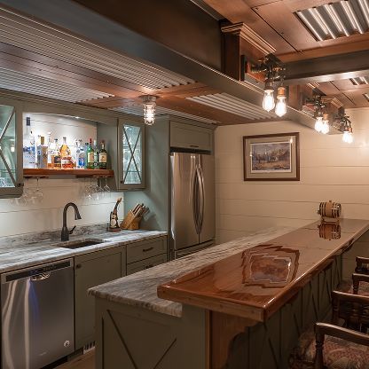 Warm modern kitchen with stainless appliances, marble island, wood cabinets, and pendant lights