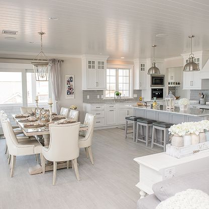 Bright white open kitchen and dining room with a set table, island stools, and pendant lights