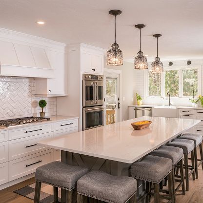 Bright modern kitchen with white cabinets, large island, pendant lights, and barstools