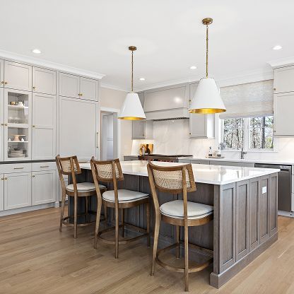 Bright modern kitchen with a large island, pendant lights, bar stools, and white cabinetry