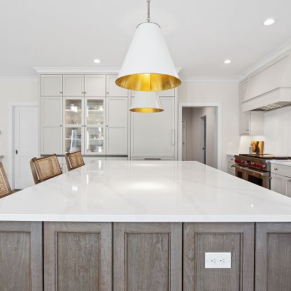 Bright modern kitchen with white island, gray cabinets, and gold pendant lights