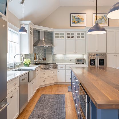 Bright modern kitchen with white cabinets, wood island countertop, stainless appliances, and pendant lights