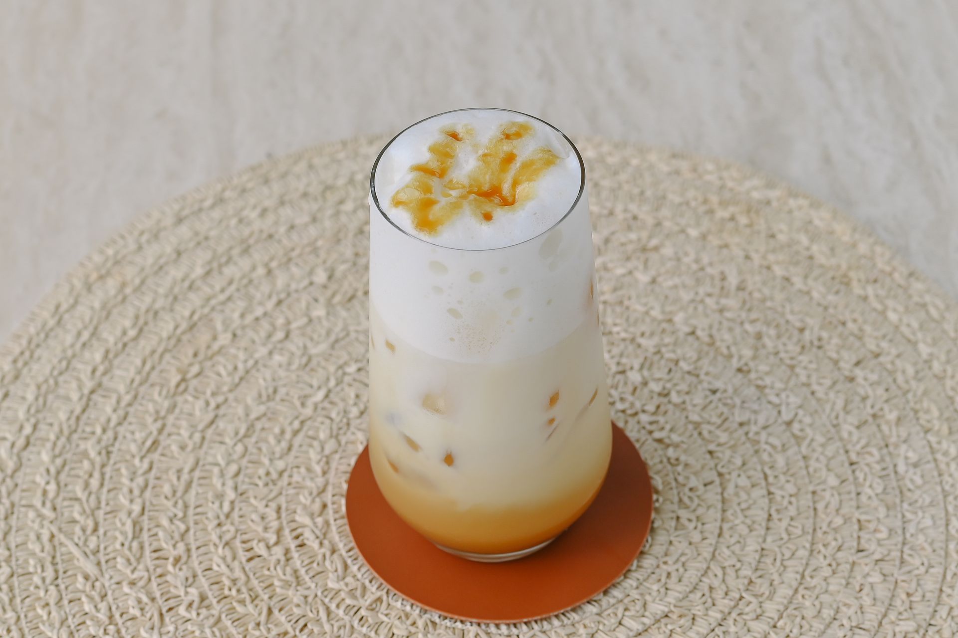 A close up of a drink in a glass on a coaster on a table.