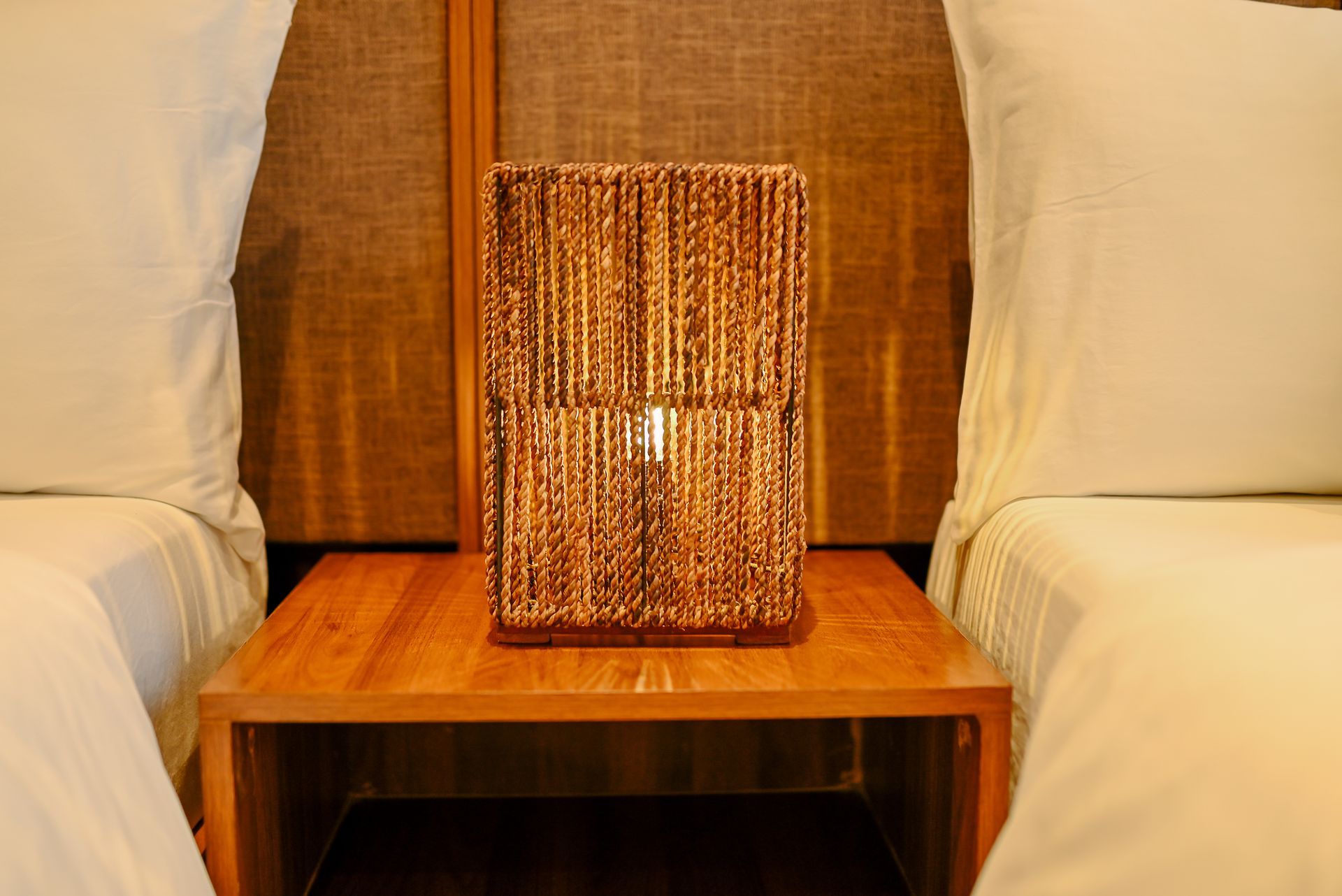 A lamp is sitting on a wooden table next to two beds.