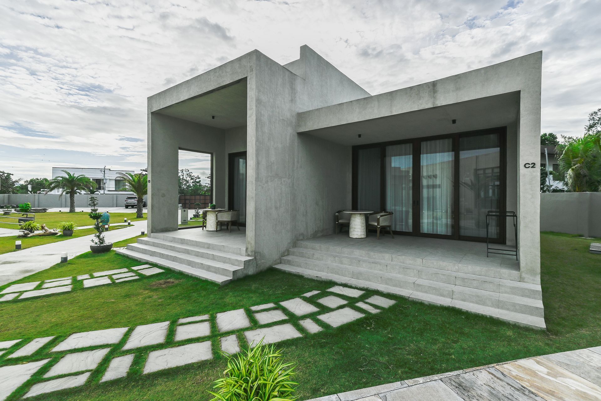 A modern concrete house with a large lawn in front of it.