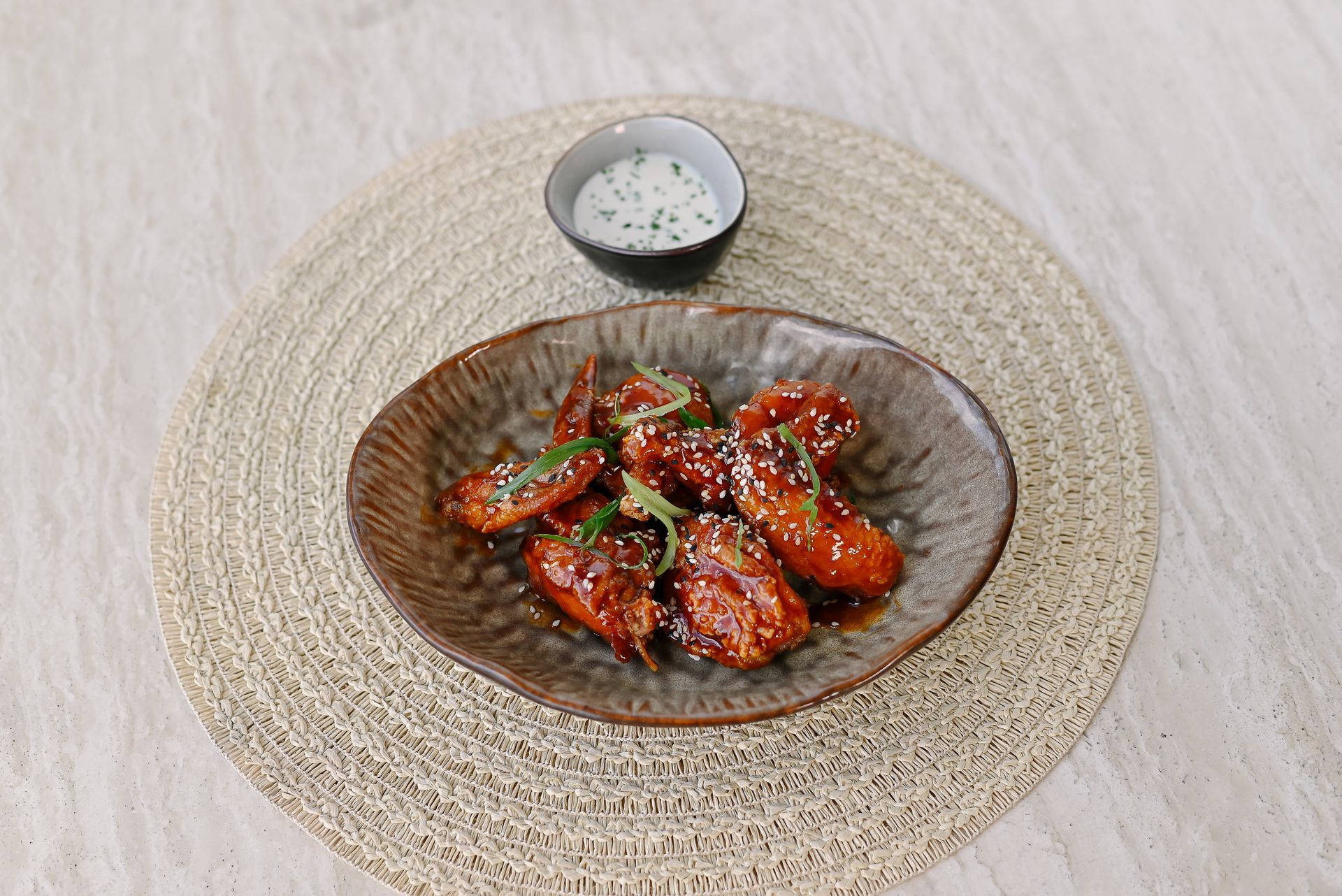 A plate of chicken wings with ranch dressing on a table.