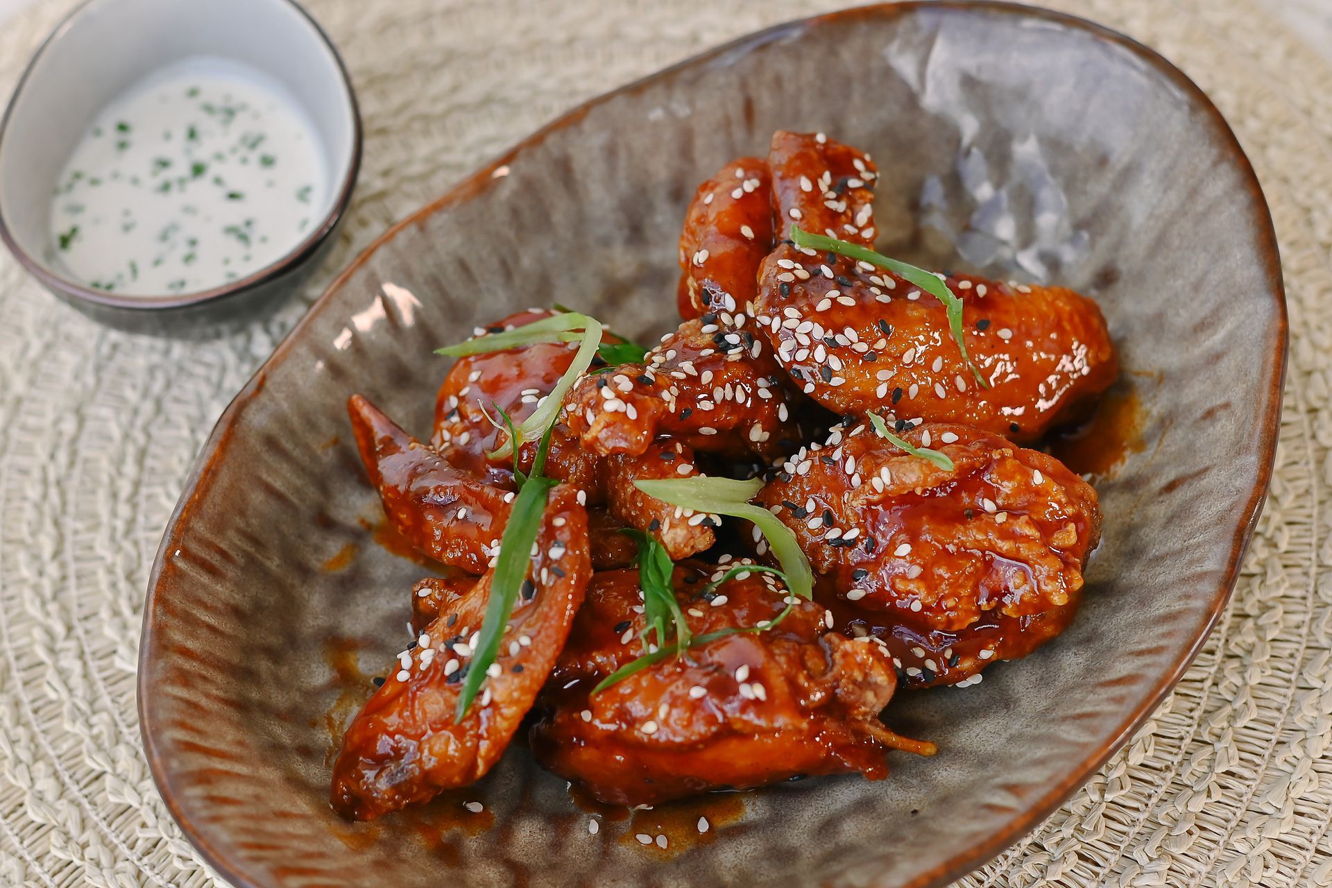 A plate of chicken wings with a side of ranch dressing on a table.