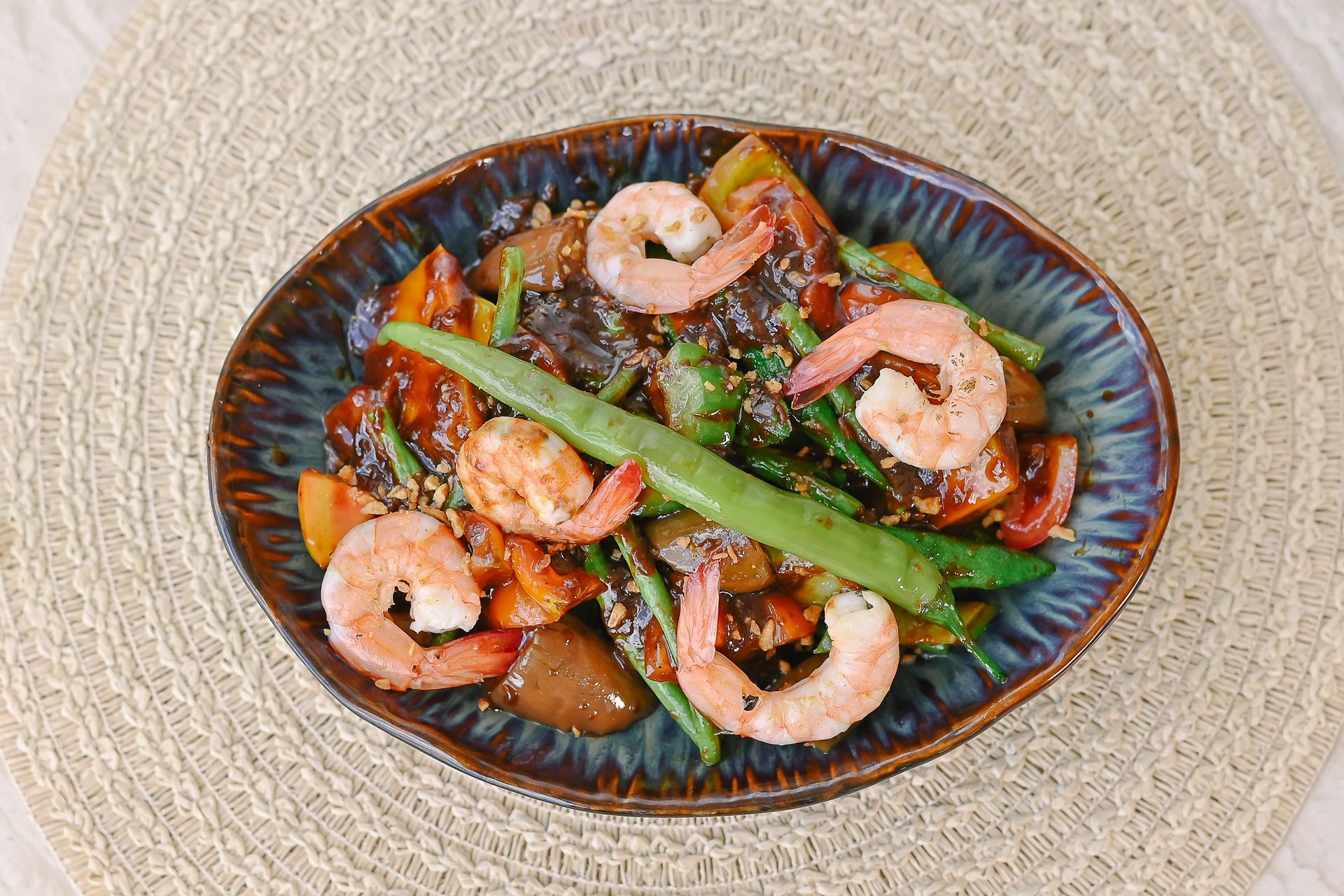 A bowl of shrimp and vegetables on a table.