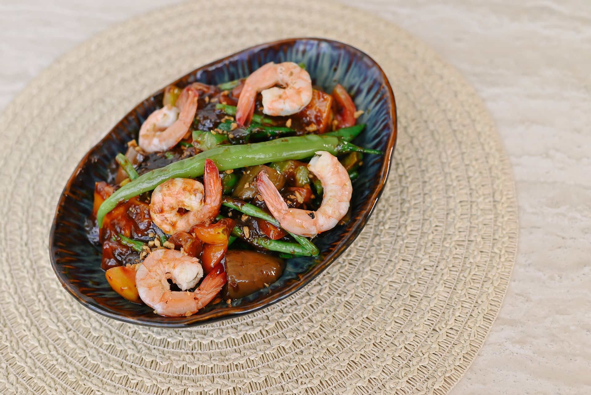 A plate of food with shrimp and green beans on a table.