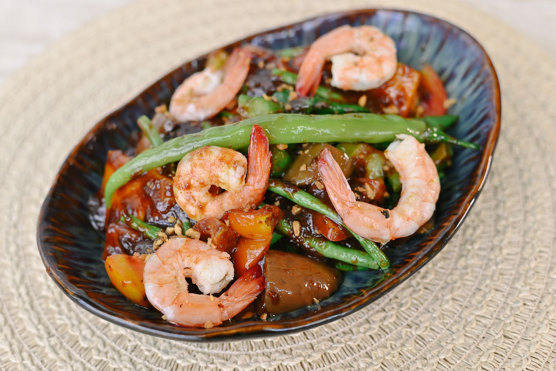 A plate of shrimp and green beans on a table.