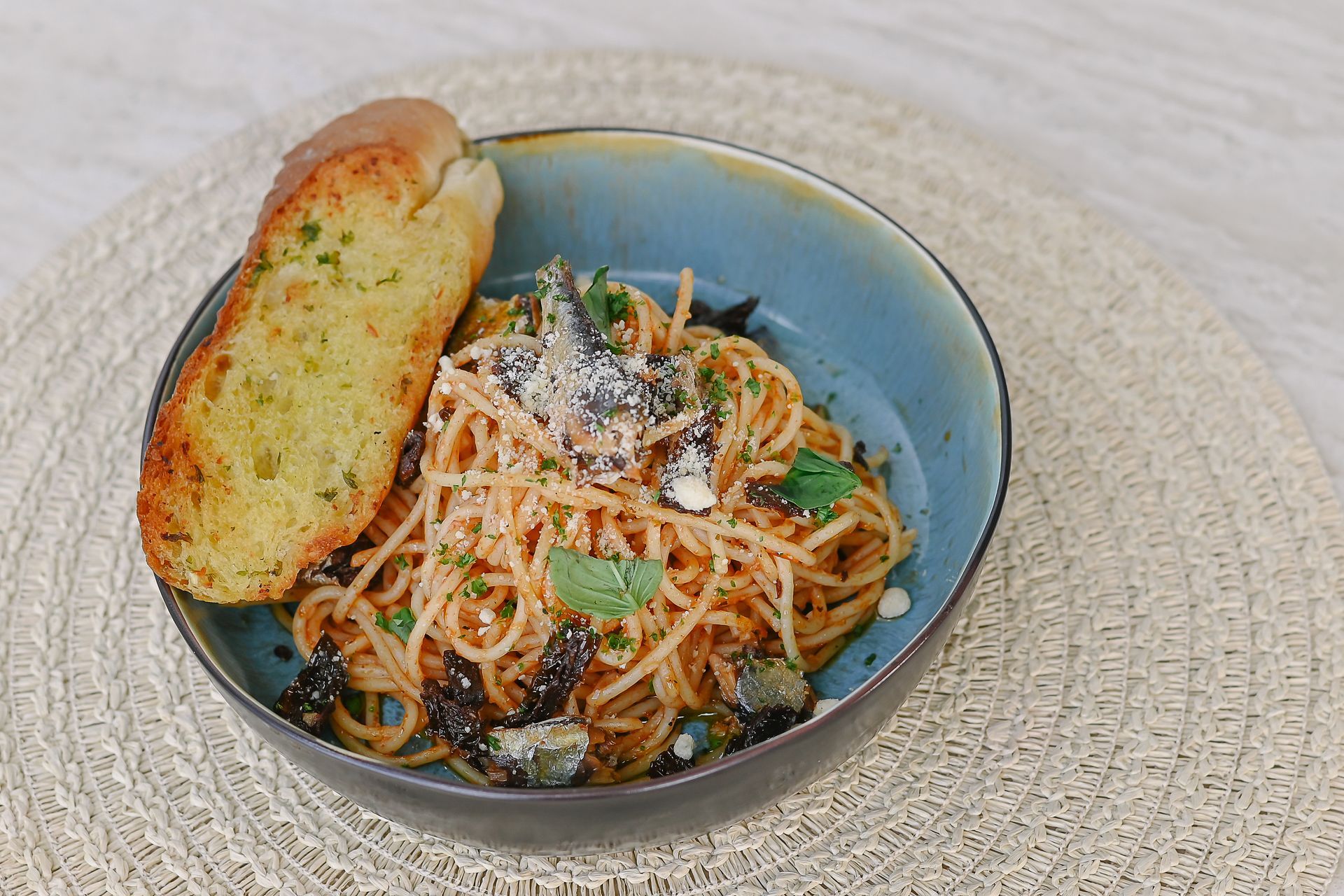 A bowl of spaghetti with garlic bread on a table.