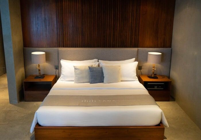 A hotel room with a bed , two nightstands and two lamps.