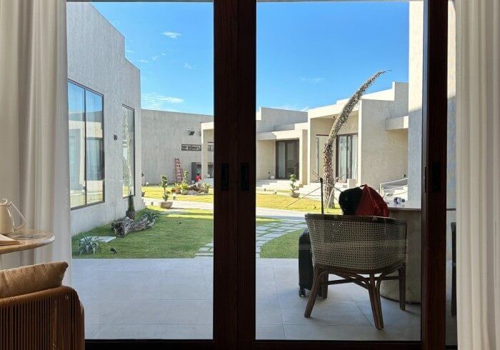 A person is sitting in a chair on a patio looking out of a window.