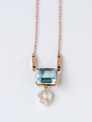 A necklace with a blue stone and a pearl on a chain.