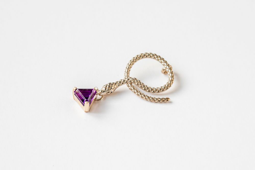 A gold ring with a purple stone on a white surface.