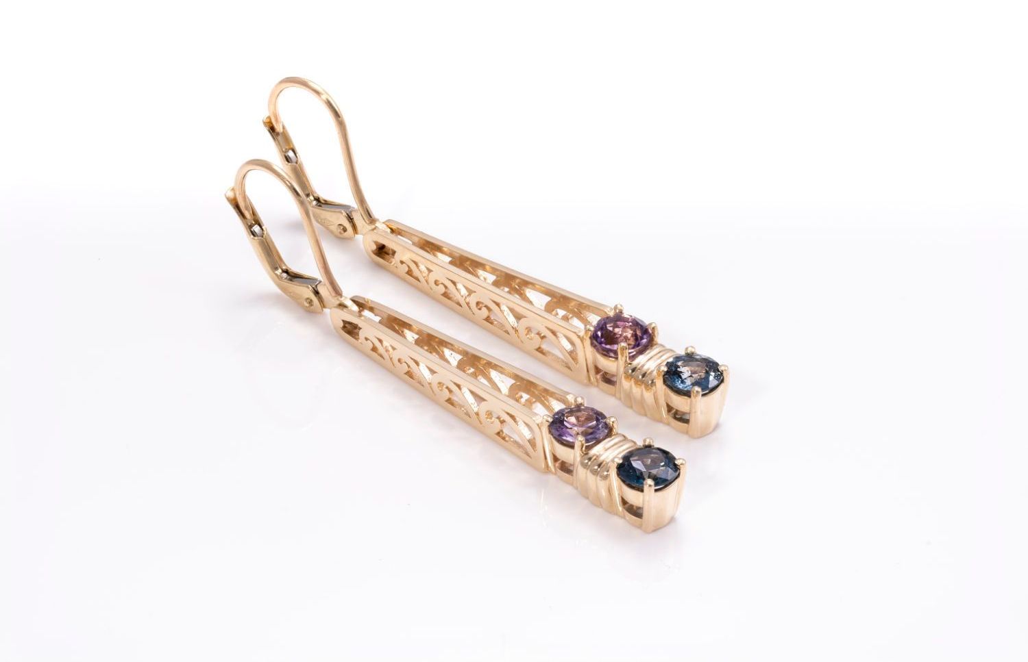 A pair of gold earrings with purple and blue stones on a white background.