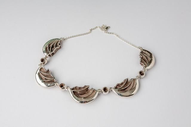 A close up of a silver bracelet on a white surface