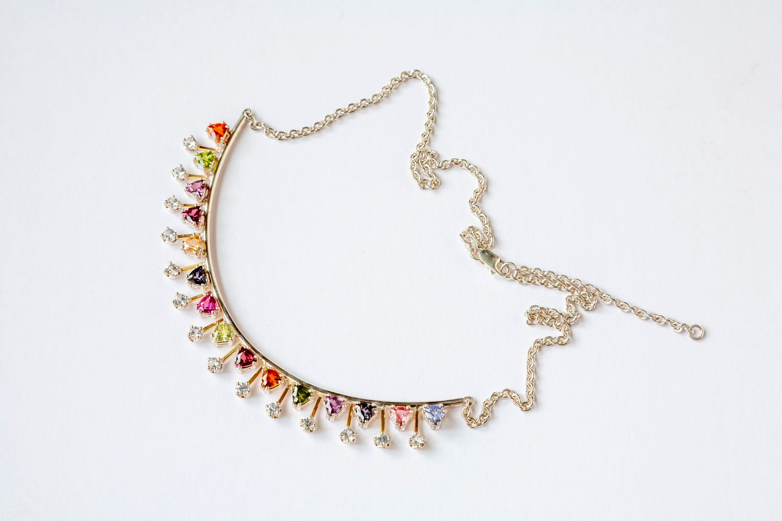 A necklace with colorful stones and rhinestones on a chain on a white background.
