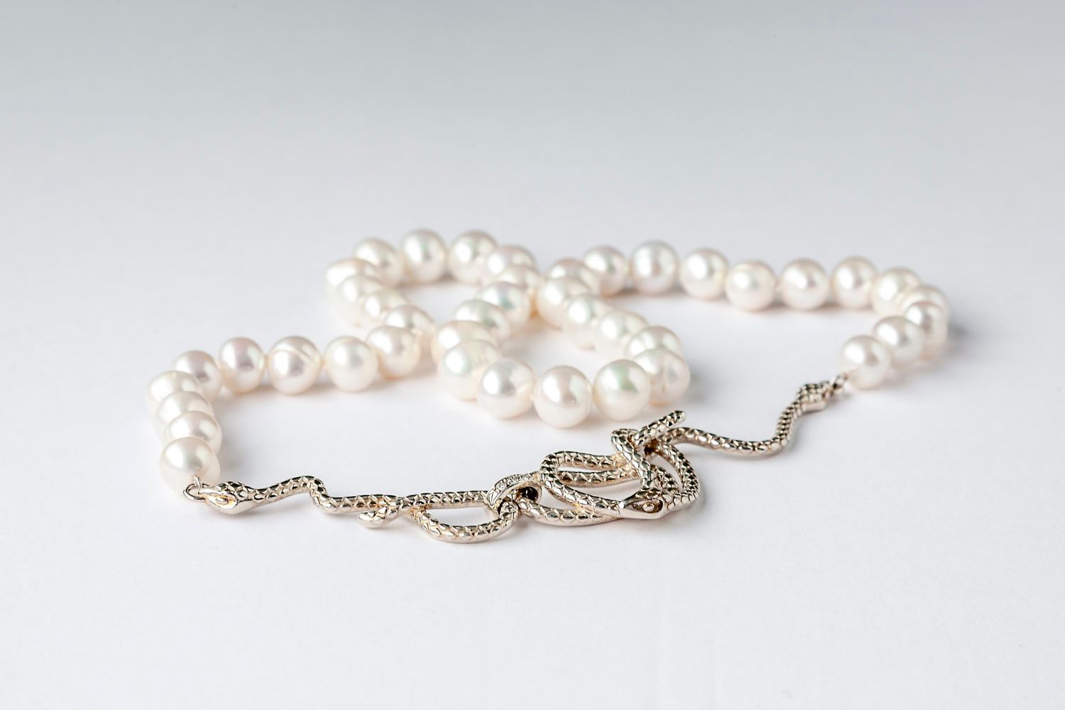 A close up of a pearl necklace on a white surface