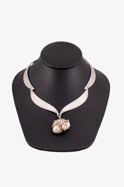 A silver necklace with a pearl pendant is on a black mannequin.