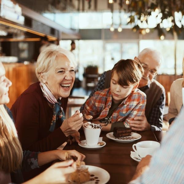 A multi-generational family enjoys desserts and conversation at a table in a warm, well-lit cafe.