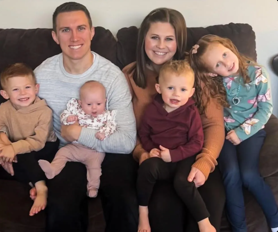 A family is posing for a picture while sitting on a couch.