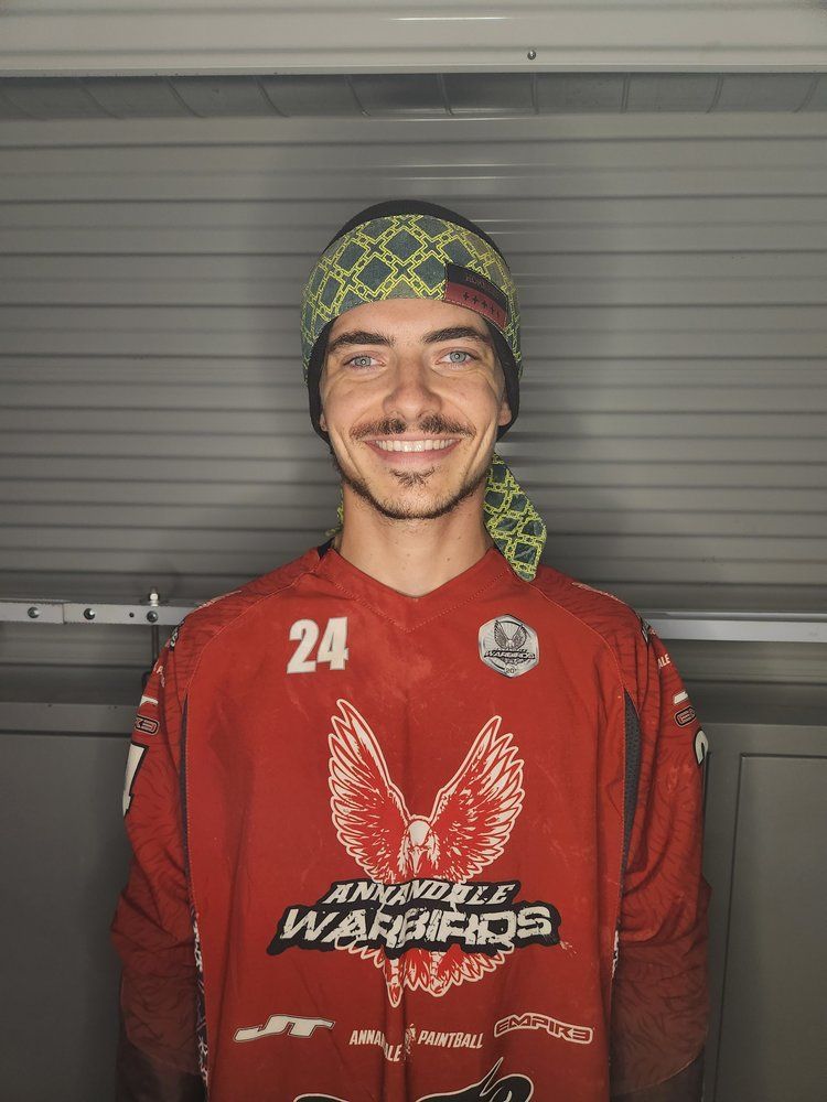 A man wearing a red jersey and a headband is smiling.