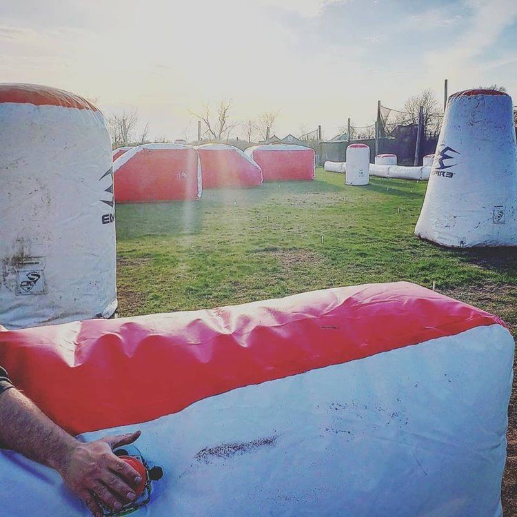 A man is sitting on a red and white inflatable couch in a field.