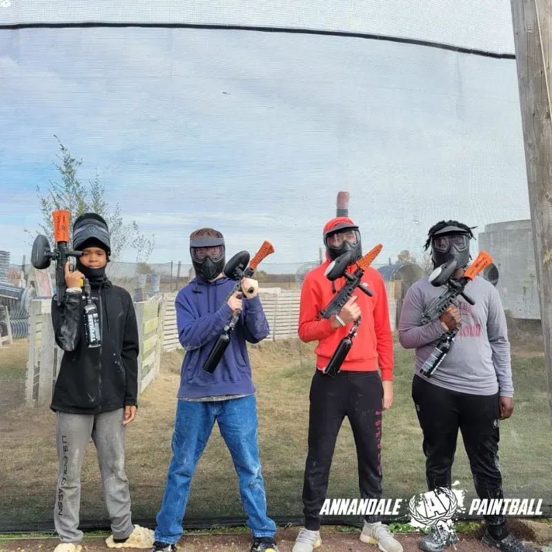 A group of people standing in front of a paintball net