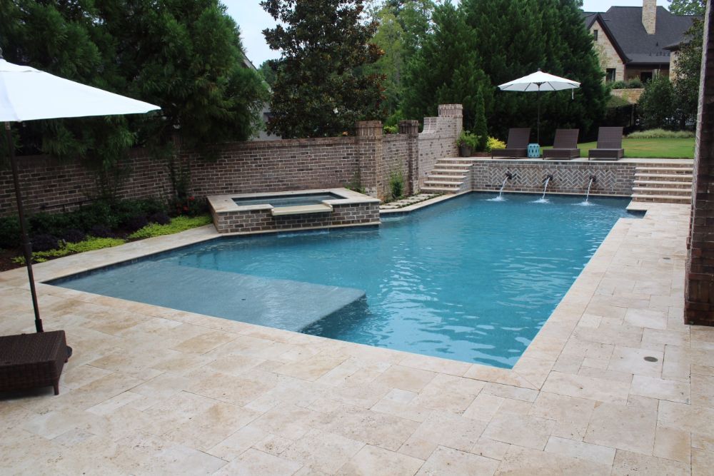 Inground geometric swimming pool and spa with ivory travertine coping and deck