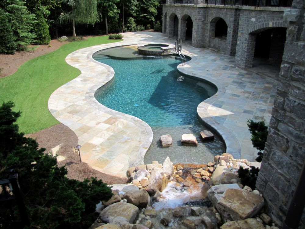 Inground swimming pool with beach entry and waterfalls