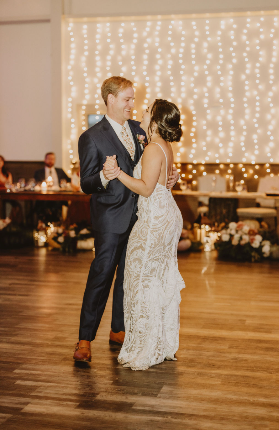 A bride and groom are dancing their first dance at their wedding reception.