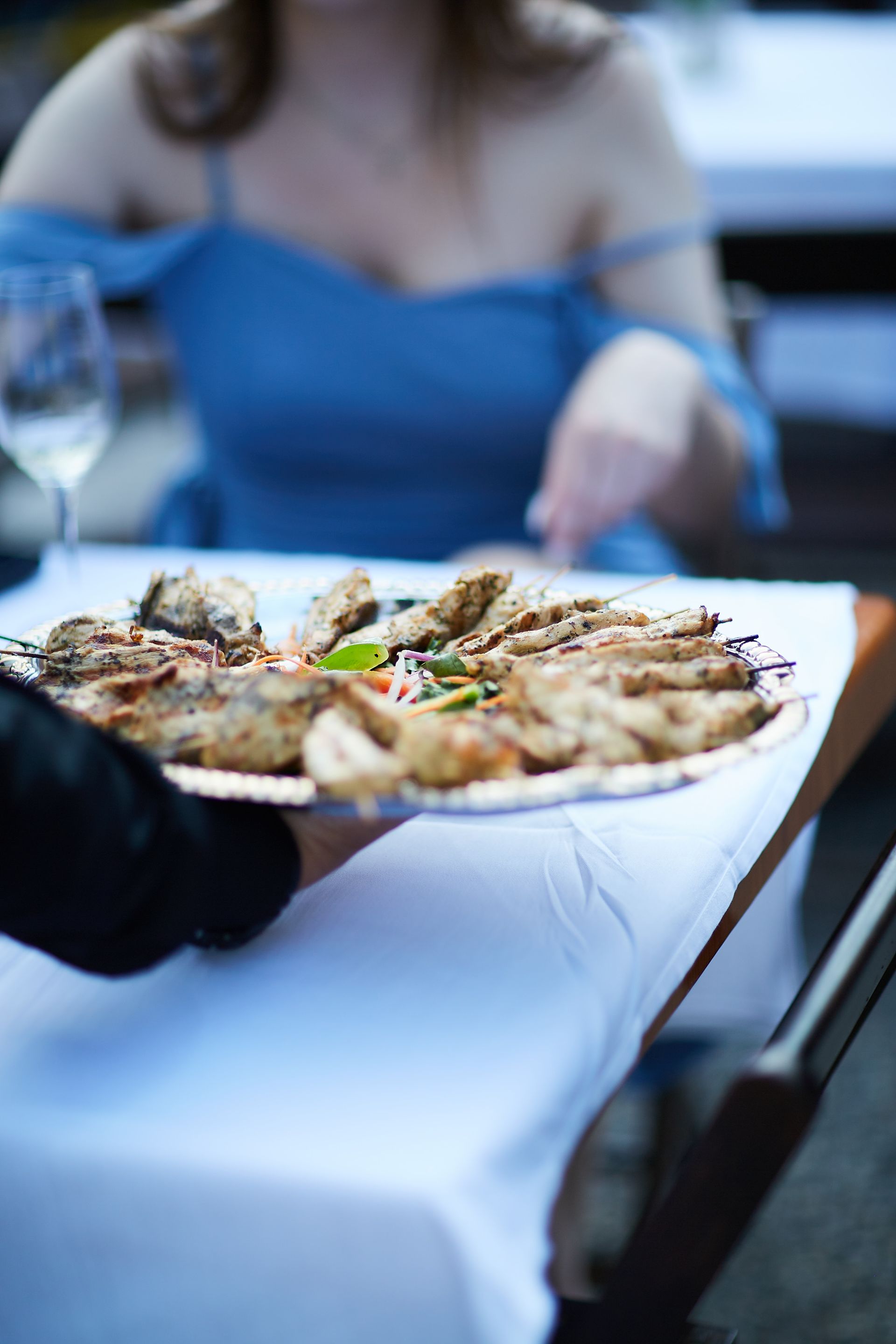A person is serving a pizza to a woman at a table.