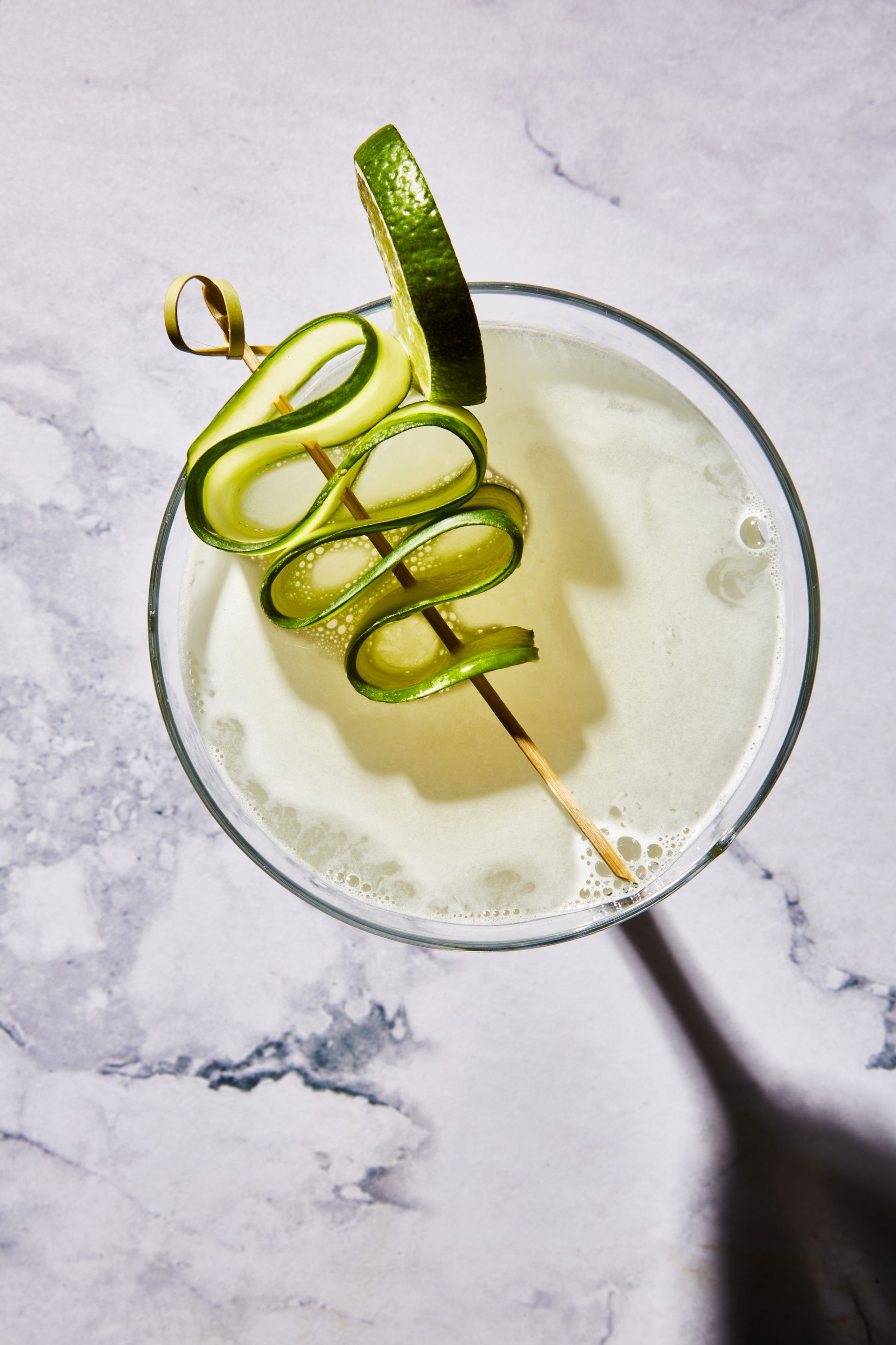 A martini with a cucumber on a stick in it