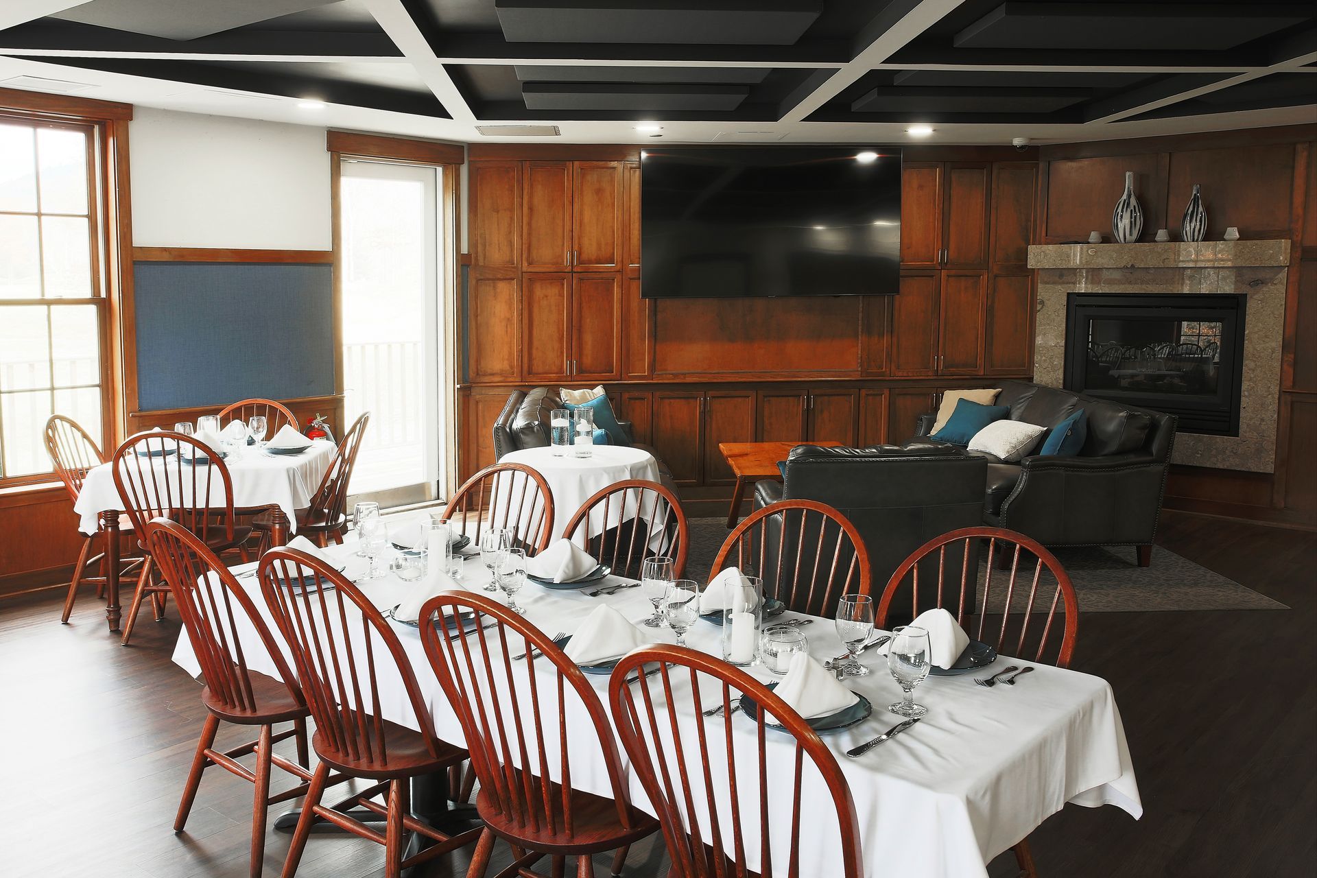 A dining room with tables and chairs and a fireplace.