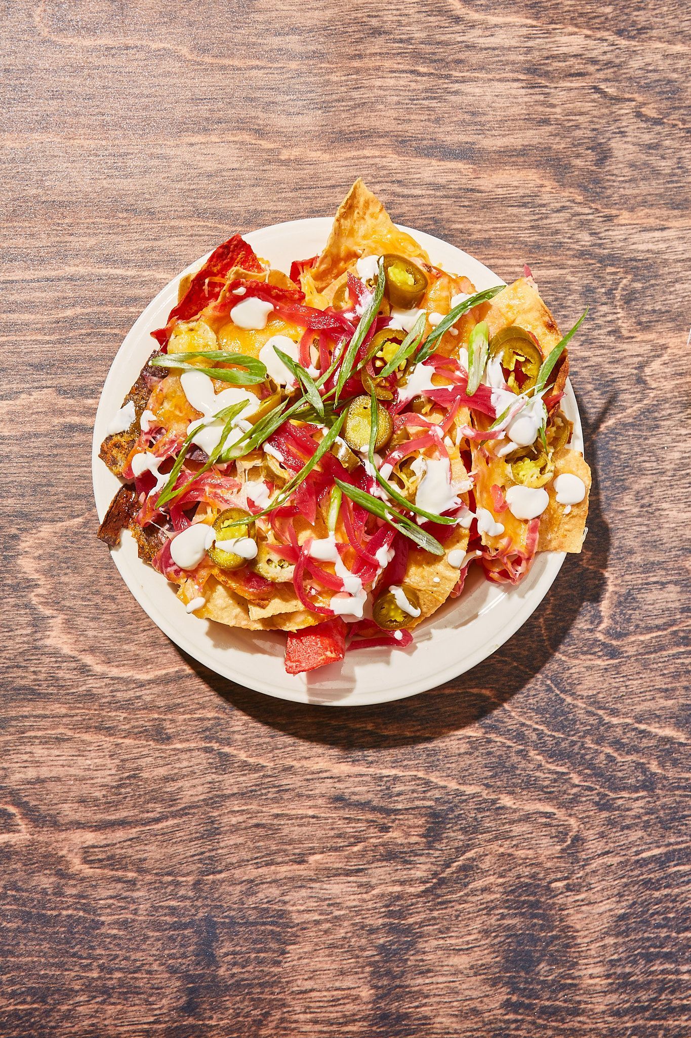 A plate of nachos on a wooden table.