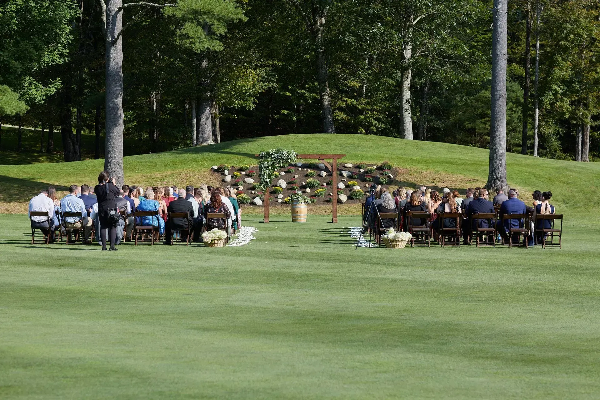 A group of people are sitting in chairs on a lush green field.