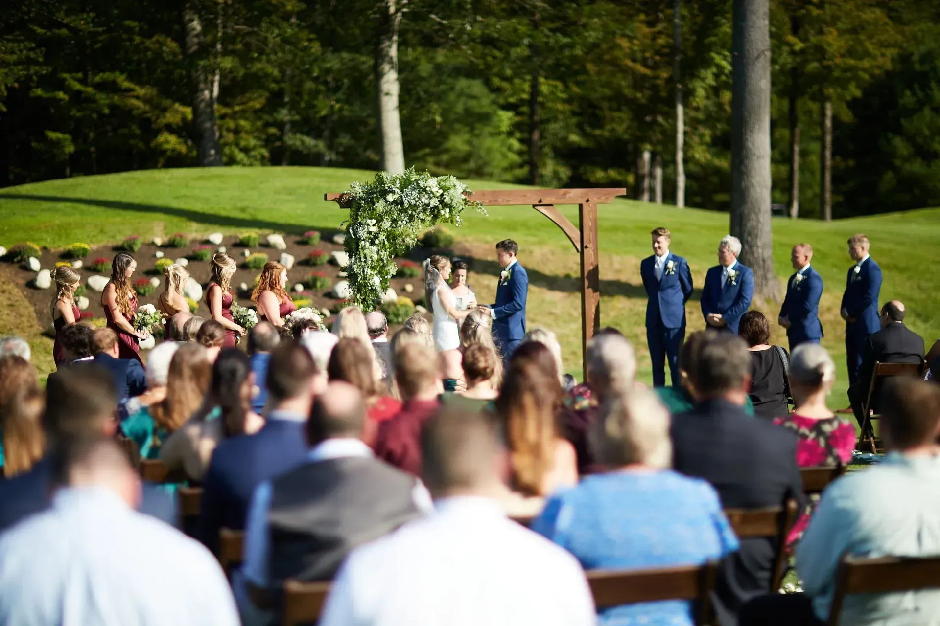 A large group of people are sitting in chairs at a wedding ceremony.