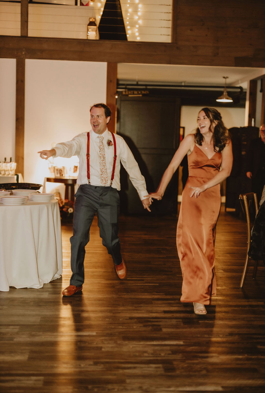 A man and a woman are holding hands and dancing at a wedding reception.