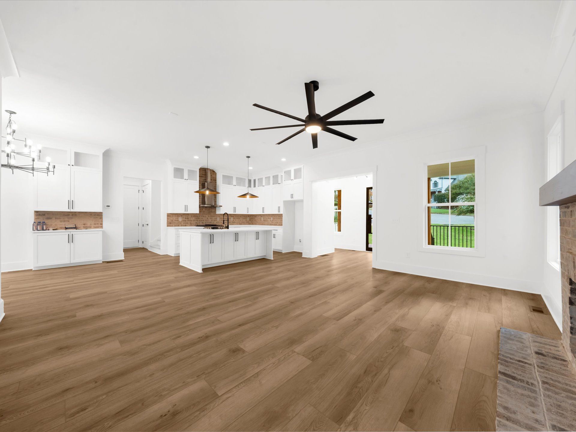 Bright open-concept living room with white walls, wood floors, and a large ceiling fan