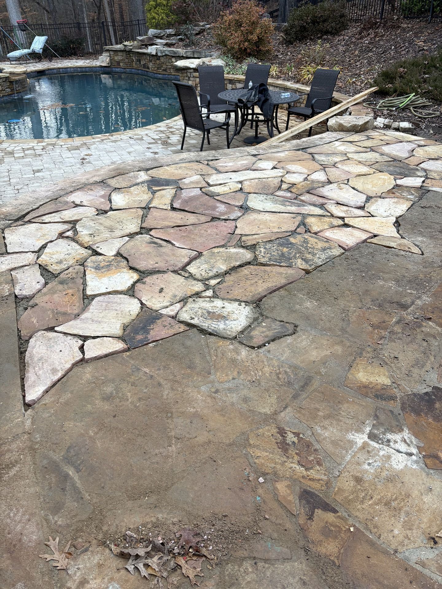 Outdoor patio with stone pavers, a pool, and a table with chairs on a patio area