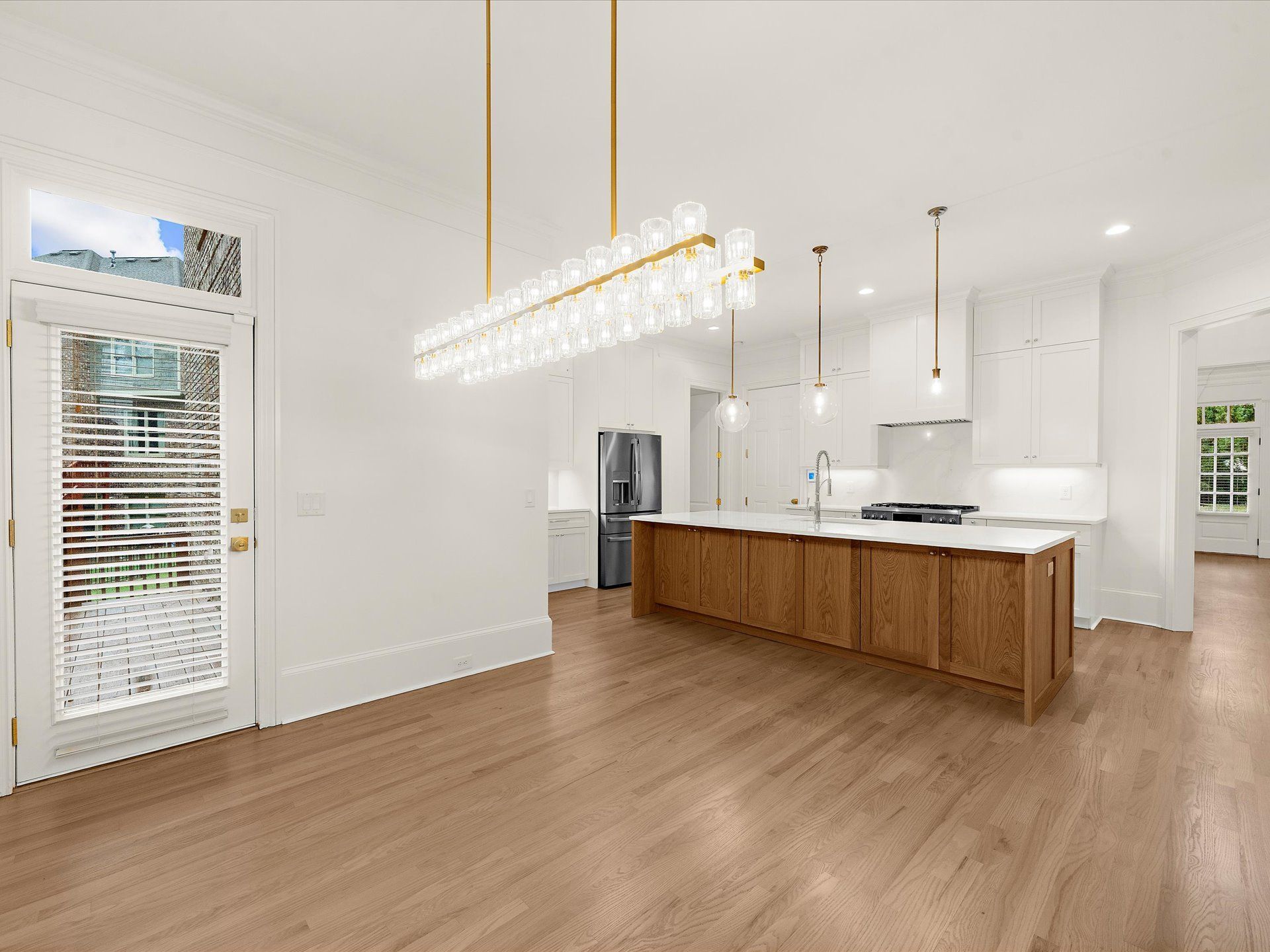Bright modern kitchen with wood island, white cabinets, pendant lights, and light wood floors