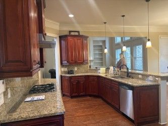 Modern kitchen with cherry cabinets, granite countertops, and stainless steel appliances, viewed from the stove area