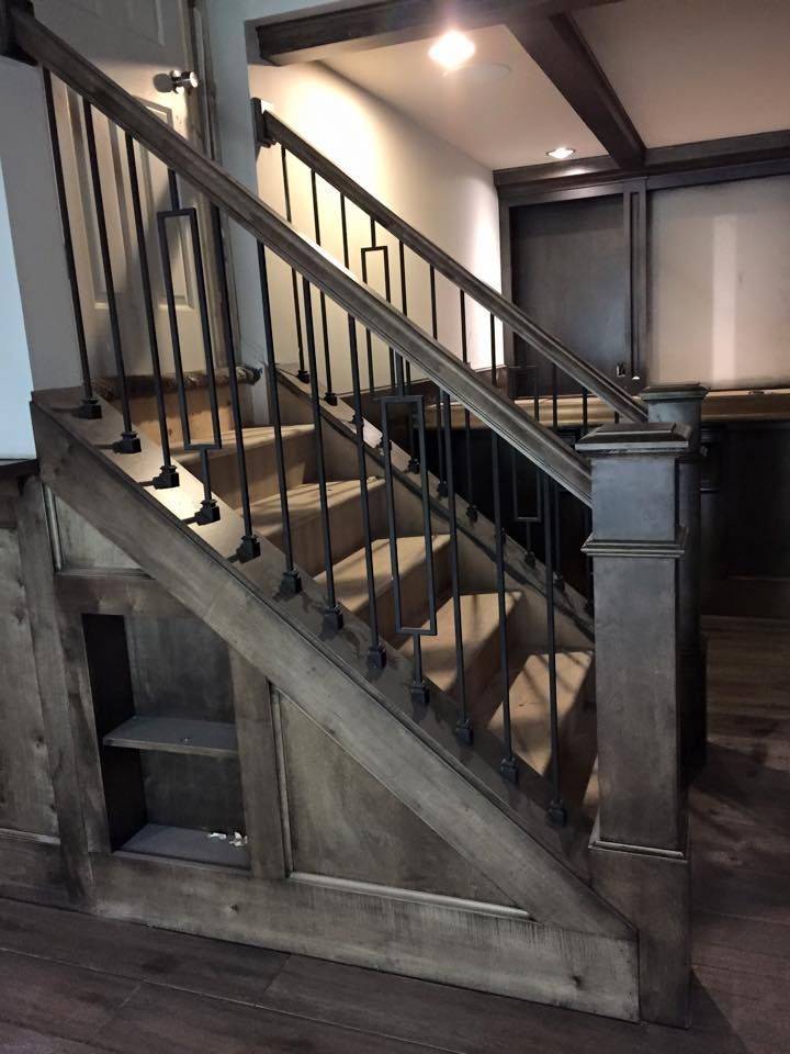 Wooden staircase with black railings and carved paneling in a dimly lit interior.