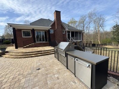Brick house with a large stone patio and outdoor storage cabinets on a sunny day
