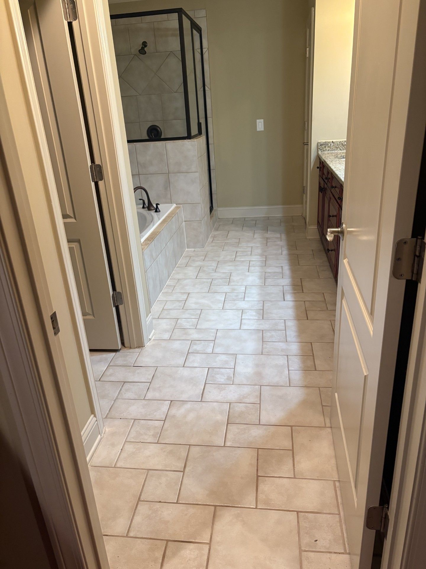 Narrow hallway leading to a tiled bathroom with a walk-in shower and vanity.