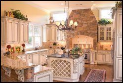 Elegant cream kitchen with island, stone range hood, chandelier, and white cabinets