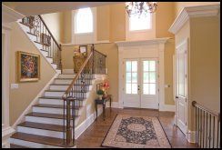 Bright foyer with staircase, chandelier, front doors, and patterned runner rug