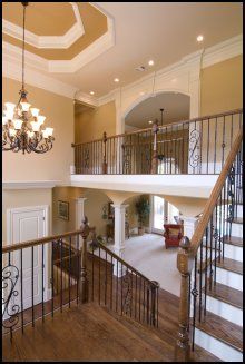 Elegant two-story foyer with wrought-iron railings, chandelier, and curved staircase